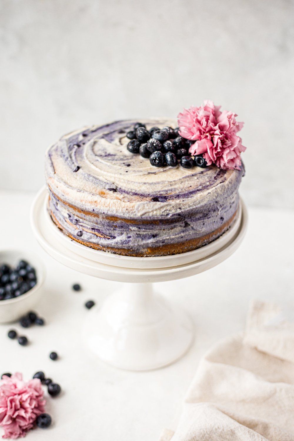 Paleo Blueberry Cake with Cashew Frosting on a cake stand food photography