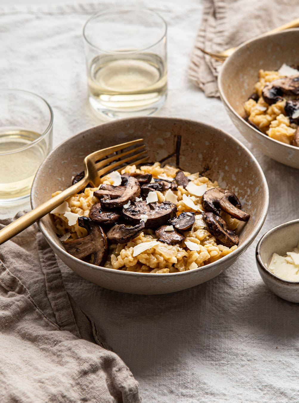 a bowl of risotto with mushrooms with gold fork