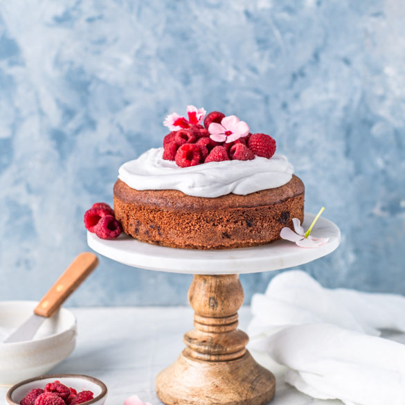 lemon cake with whipped cream and raspberries on wooden cake stand food photography