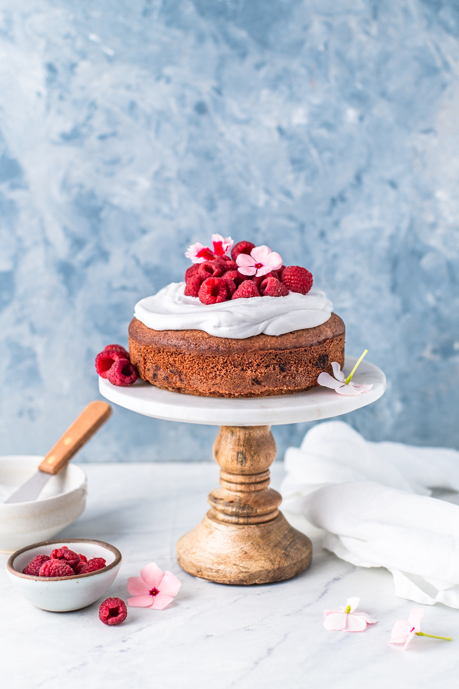 Lemon raspberry cake with coconut whipped cream on a cake stand