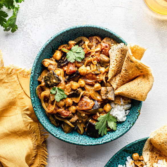 Roasted Eggplant Curry bowl with chickpeas cilantro and chickpea pancake in a blue bowl food photography