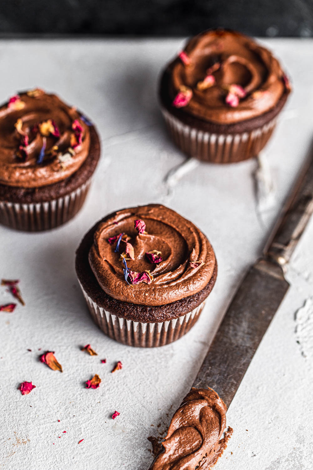 keto chocolate cupcakes with chocolate frosting and edible flowers food photography
