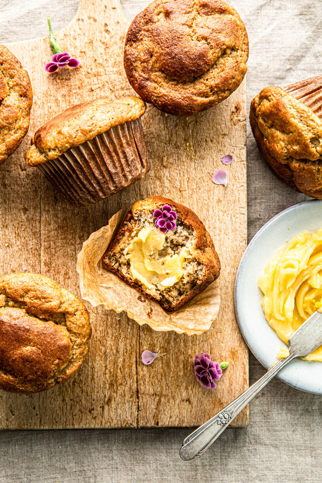 paleo muffins with a bite taken out with honey butter and flower petals
