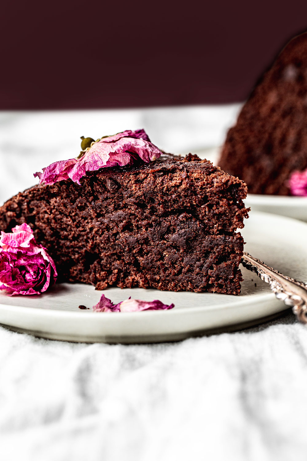 slice of moist chocolate cake on a plate with edible roses