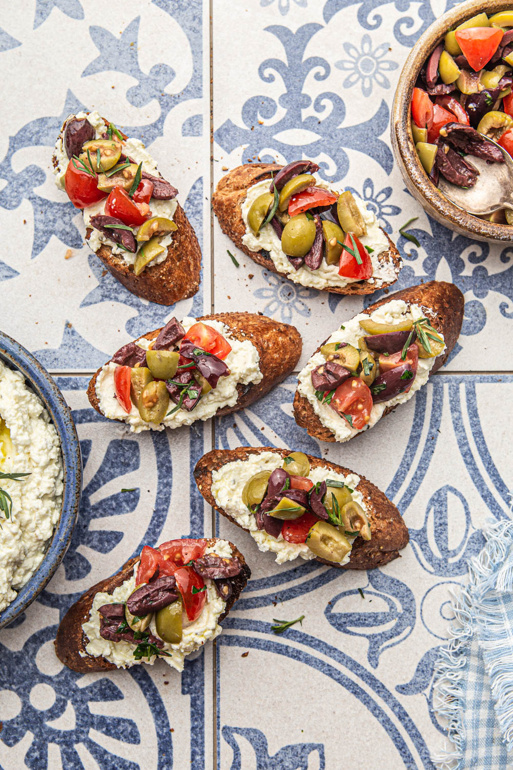 Olive Bruschetta with Whipped Feta on a Mediterranean tile backdrop food photography