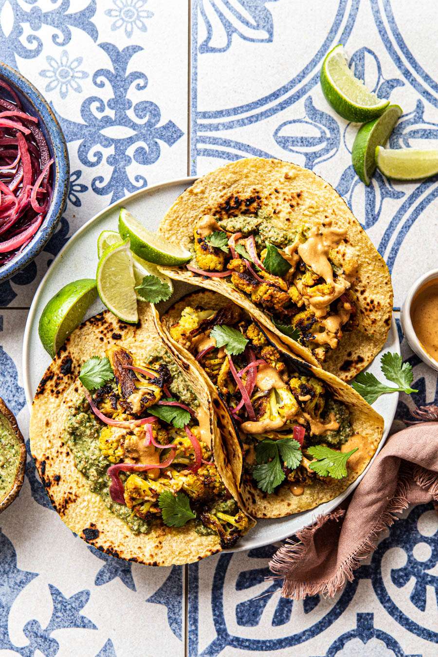 vegan cauliflower tacos with pesto chipotle crema and pickled red onions on a blue backdrop food photography