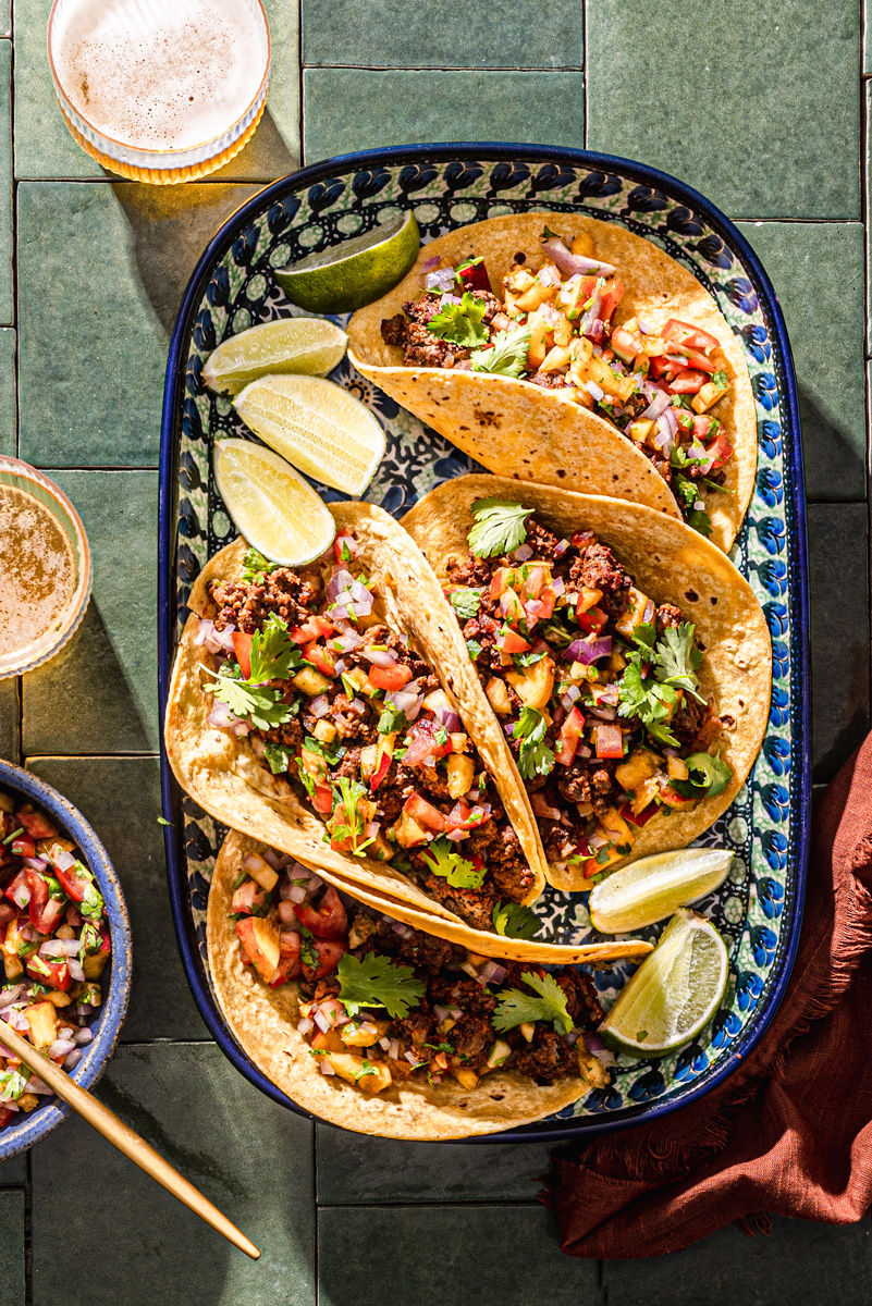 spicy beef tacos with peach salsa on green tiles