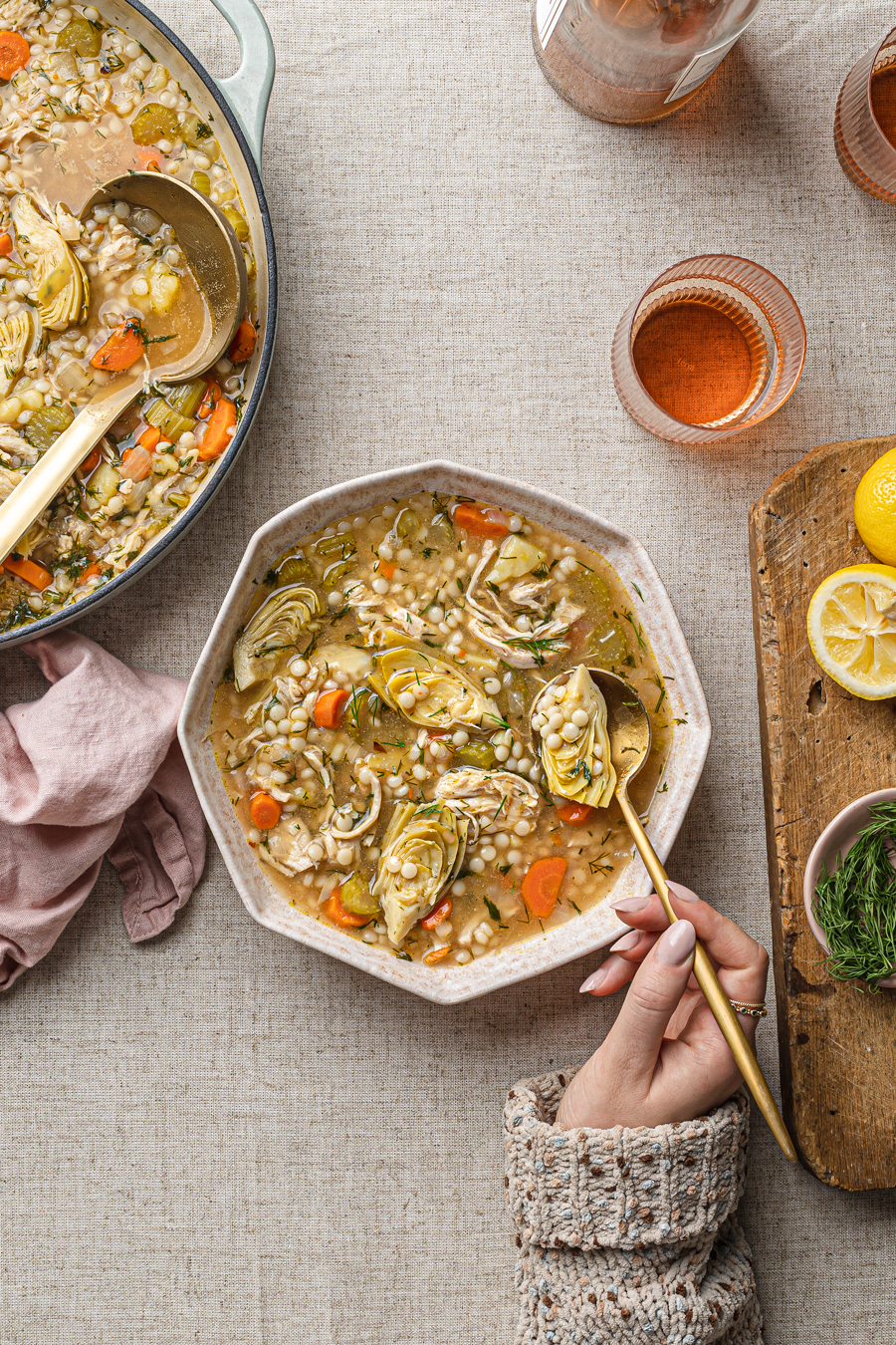 lemon chicken soup with hand grabbing a spoon food styling food photgoraphy